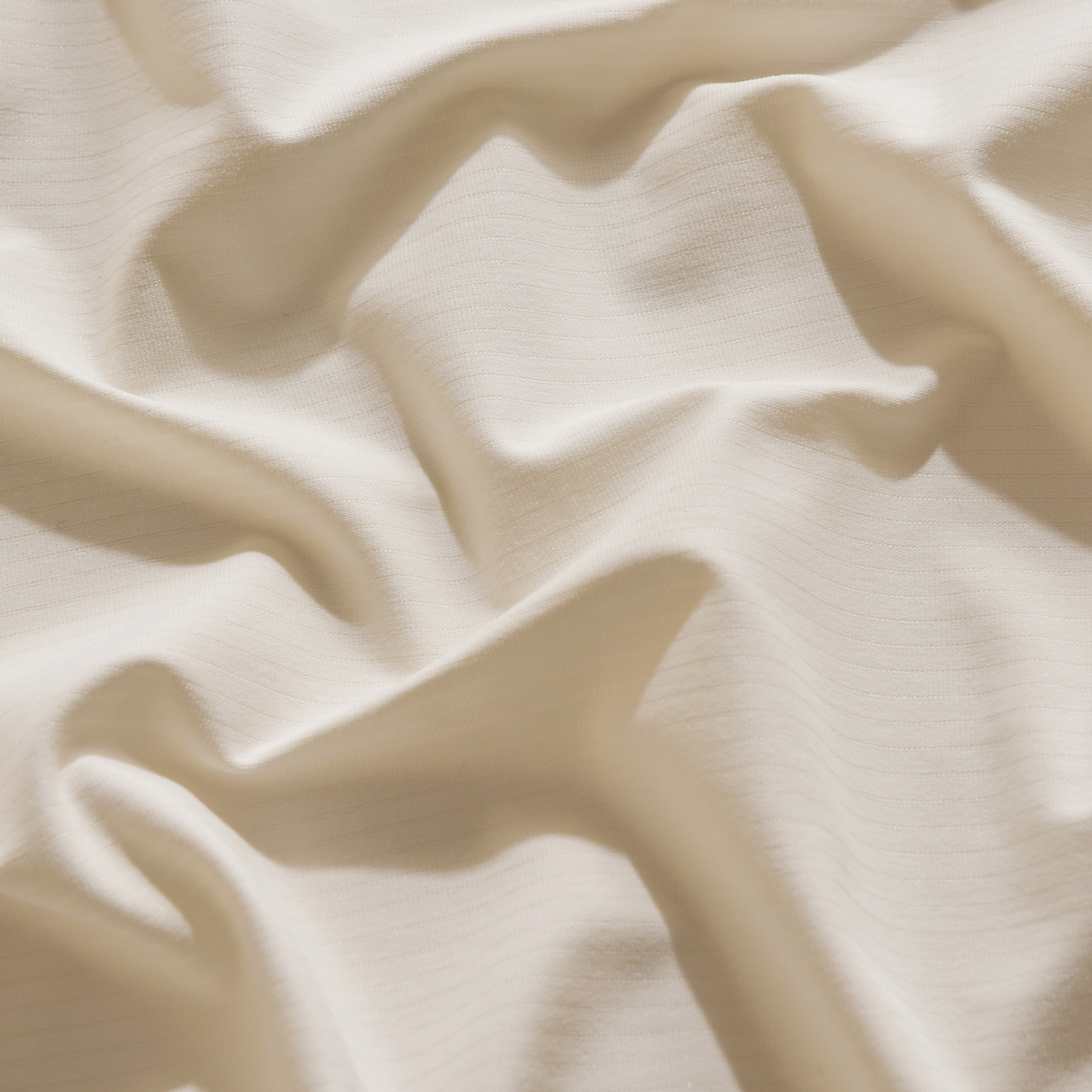 Cream-colored fitted sheet on a bed, labeled hypoallergenic and ideal for allergy-prone sleepers