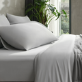 Complete gray bedding set including fitted sheet and pillowcases arranged on a bed, emphasizing seamless cooling coverage