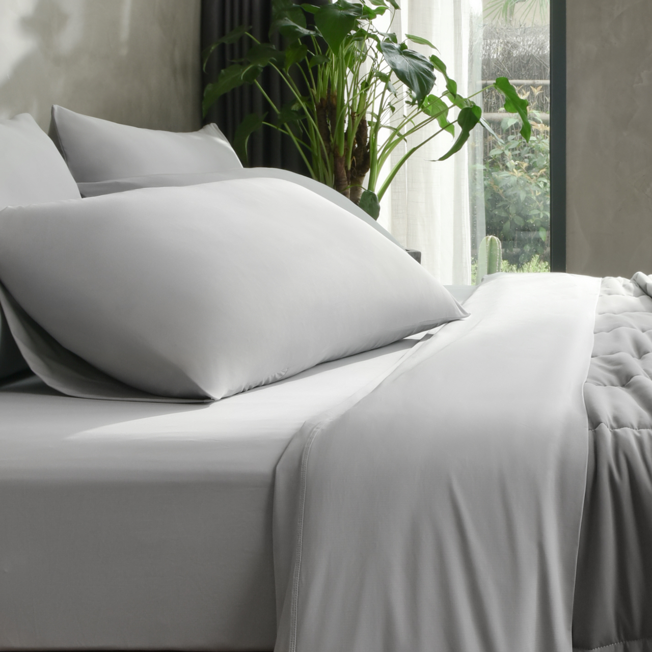 Complete gray bedding set including fitted sheet and pillowcases arranged on a bed, emphasizing seamless cooling coverage