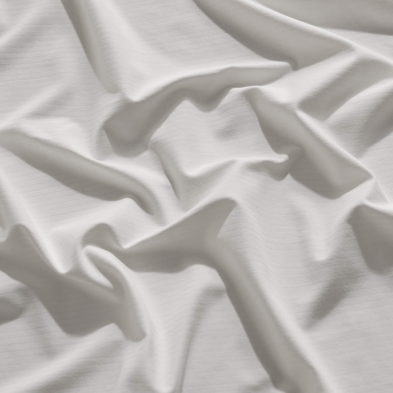 White fitted sheet stretched over a queen-size mattress, showing flexibility and snug fit